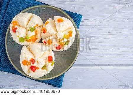 Top View Of Thai Steamed Cupcakes Topped With Dry Fruit On A Plate On A Blue Cloth With A Wooden Bac