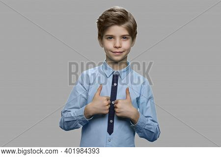Child Boy Giving Thumbs Up Against Gray Background. Portrait Of Handsome Kid Giving Approval Sign On