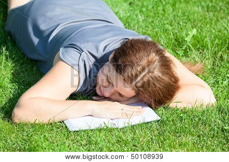 Caucasian Woman Asleep While Reading Book On Green Summer Meado