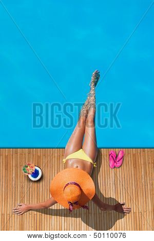 Young woman reaxing on the deck by the swimming pool at exotic resort