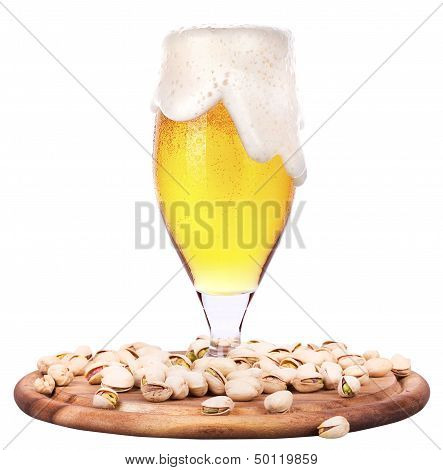Frosty glass of light beer with pistachos