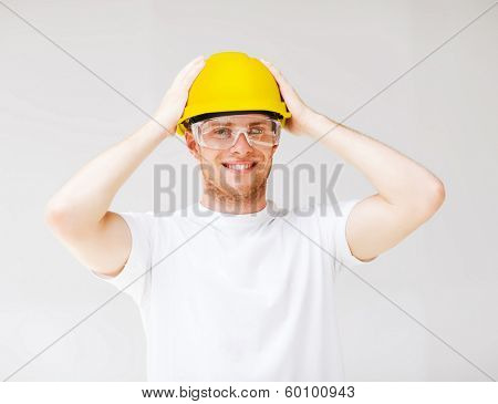 building, developing, consrtuction and architecture concept - picture of male builder in safety glasses and yellow helmet