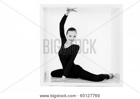 Modern ballet dancer posing with a cube at studio. Plastic body concept. Isolated over white.