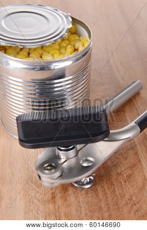 Can piercer with canned on wooden background