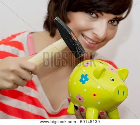 Young Woman Breaks A Porcelain Piggy Bank With A Hammer