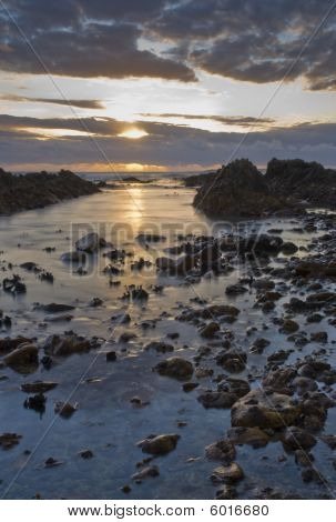 岩の多い水に沈む夕日