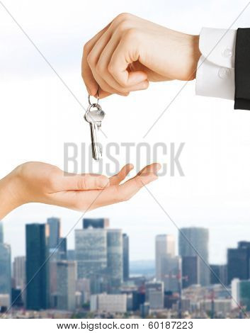 real estate and banking concept - close up of man hand passing house keys to woman