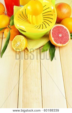Citrus press and fruits on wooden background
