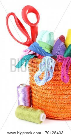 Round orange box full of multicoloured threads and everything necessary for sewing on white background isolated