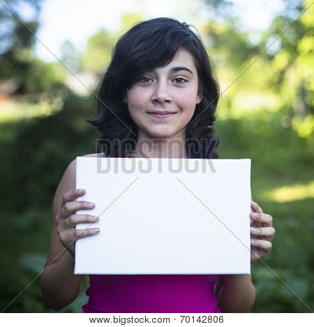 Teengirl holding clean white sheet paper, outdoors (banner for your message)