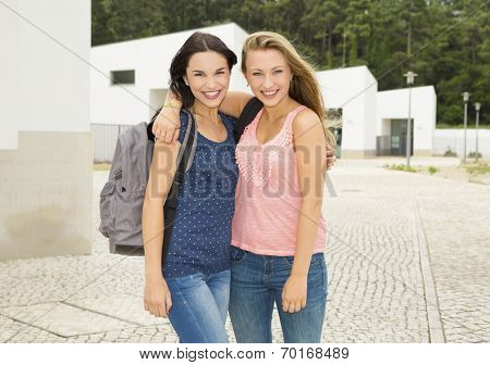 Two beautiful and happy teenage students lauthing 