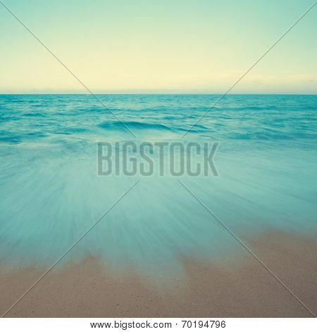 Vintage beach scene in sunset, slow shutter with moving waves.
