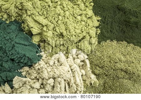 background of five healthy green dietary supplement powders (spirulina, chlorella, wheatgrass, kelp and moringa leaf)