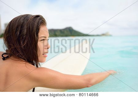 Surfer girl surfing paddeling on surfboard. Female surf bikini woman living healthy active water sports lifestyle on Hawaiian beach. Asian Caucasian model on Waikiki Beach, Oahu, Hawaii.