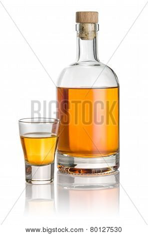Bottle and shot glass filled with amber liquid