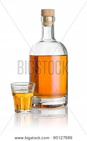 Bottle and beveled shot glass filled with amber liquid