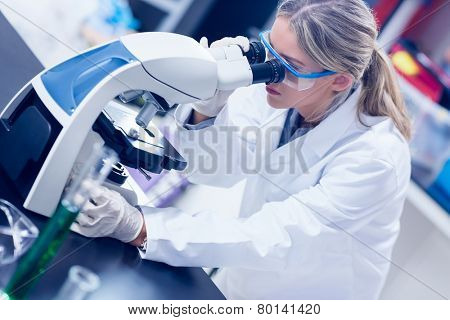 Science student looking through microscope in the lab at the university