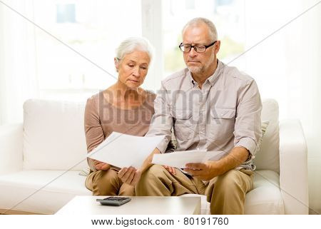family, business, savings, age and people concept - smiling senior couple with papers and calculator at home