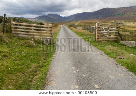Minor Road Leading Into Valley Surrounded By Mountains.
