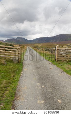 Minor Road Leading Into Valley Surrounded By Mountains.