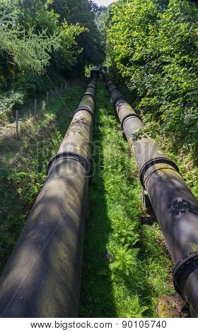 Two Large Black Water Pipes, Converging In Distance.