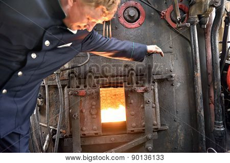 ST. PETERSBURG, RUSSIA - MAY 7, 2015: Machinist assistant opens the firebox of a steam locomotive. The parade of steam locomotives dedicated to the WWII Victory Day