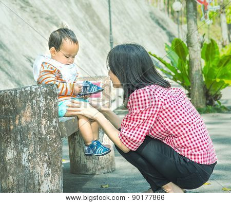 Mother wearing shoe to baby