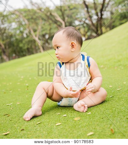 baby sitting on the grass field at outdoor park