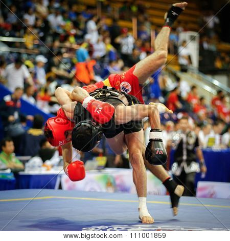 JAKARTA, INDONESIA - NOVEMBER 15, 2015: Jafar Topraghlou of Iran (black) throws Jorge Cortez of USA (red) in the men's 65kg Sanda event at the 13th World Wushu Championship 2015 in Istora Senayan.