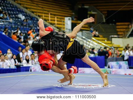 JAKARTA, INDONESIA - NOVEMBER 15, 2015: Puja Riyaya of Indonesia (red) fights Van Tai Nguyen of Vietnam (black) in the men's 70kg Sanda event at the 13th World Wushu Championship 2015 in Jakarta.