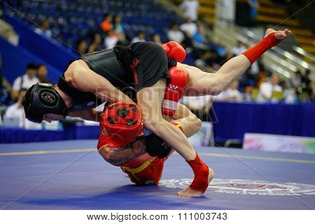 JAKARTA, INDONESIA - NOVEMBER 15, 2015: Caio Pitoli of Brazil (red) fights Radek Vermirovsky of Czech Republic (black) in the men's 70kg Sanda event at the 13th World Wushu Championship 2015.