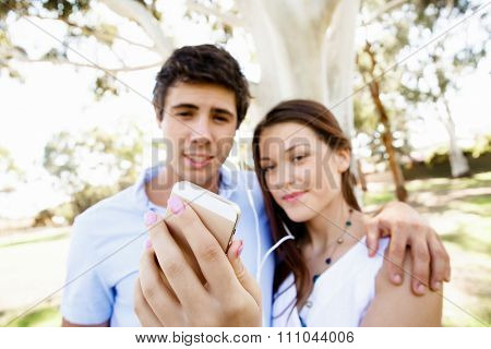 Young couple in the park making their selfi with mobile phone