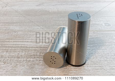 Stainless steel salt and pepper shakers on wooden table