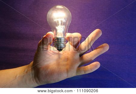 Lighting lamp flashing bulb in human hand on blue background