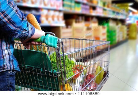 Man Pushing Shopping Cart In The Supermarket Aisle