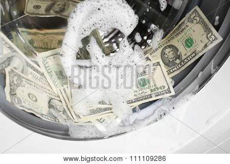 Laundering of dirty money in washing machine, close up