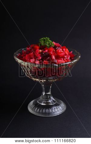 salad with beets and potatoes in a glass vase on a black background