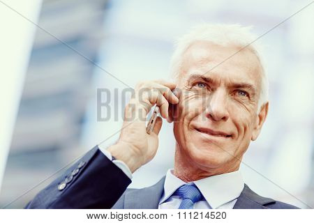 Portrait of confident businessman with his mobile phone outdoors
