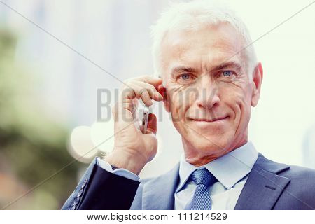 Portrait of confident businessman with his mobile phone outdoors