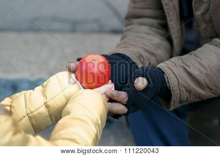 Child gives apple to the beggar.
