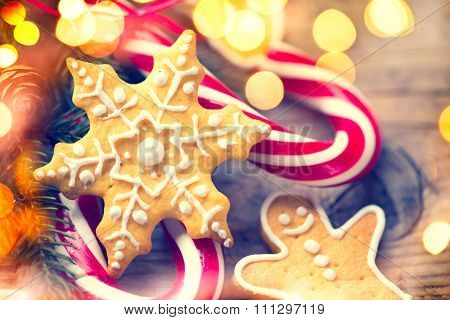 Christmas Holiday Background with Gingerbread cookies, Candy Cane and evergreens border over wooden table. Christmas and New year food. Christmas decoration and sweets on wood background