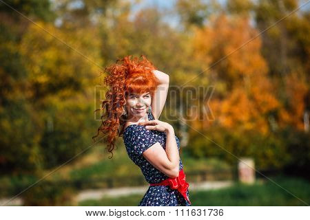 beautiful sexy red-haired girl in a blue dress walks in the autumn park