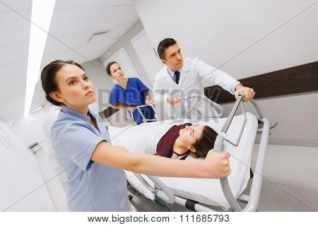 profession, people, health care, reanimation and medicine concept - group of medics or doctors carrying woman patient on hospital gurney to emergency