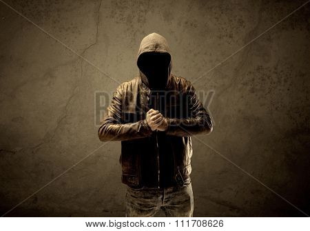 A suspicious faceless mature male in dark urban environment and light in front of a concrete empty wall background