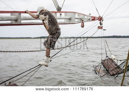 BEAUFORT, SOUTH CAROLINA-OCTOBER 16, 2015: Unidentified worker climbs the rigging on a fishing vessel off the coast of Beaufort, South Carolina