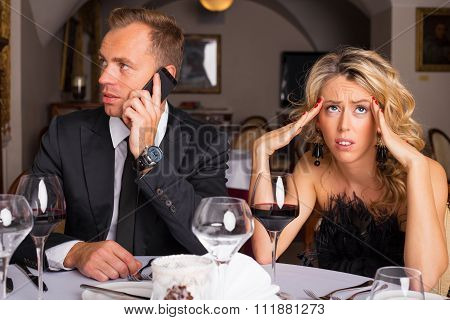 Woman at dinner date being annoyed of man talking on the phone