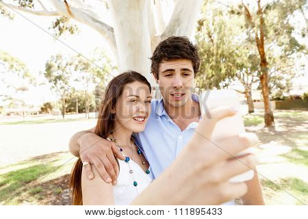 Young couple in the park making their selfi with mobile phone