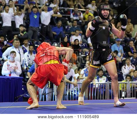JAKARTA, INDONESIA - NOVEMBER 18, 2015: Kazbek Mamaev of Russia (red) fights Seungmo Park of South Korea (black) in the men's 65kg Sanda event at the 13th World Wushu Championship 2015.
