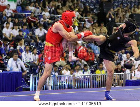 JAKARTA, INDONESIA - NOVEMBER 18, 2015: Jafar Tropraghlou of Iran (red) fights Ji Fu Xu of China (black) in the men's 65kg Sanda event at the 13th World Wushu Championship 2015.