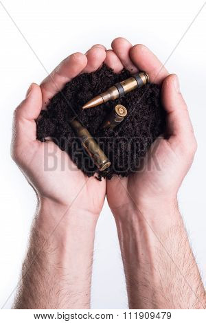 Hands Holds Topsoil With Bullets